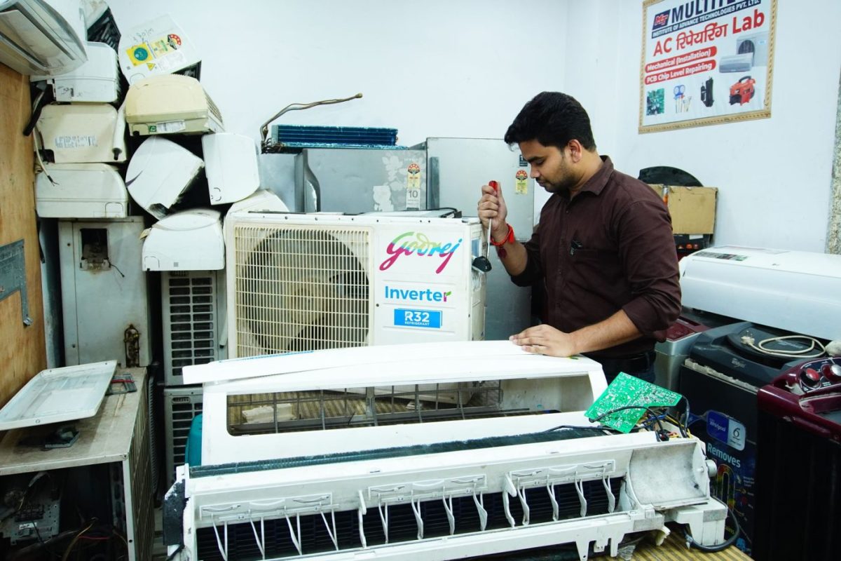 A technician uses a digital gauge to measure the cooling output of a built-in refrigerator in a modern residential kitch