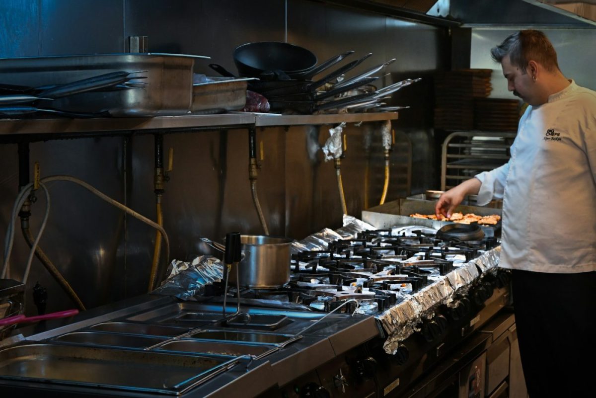 A chef works on a commercial mixer in a soundproofed restaurant kitchen with anti-vibration mounts visible under the equ