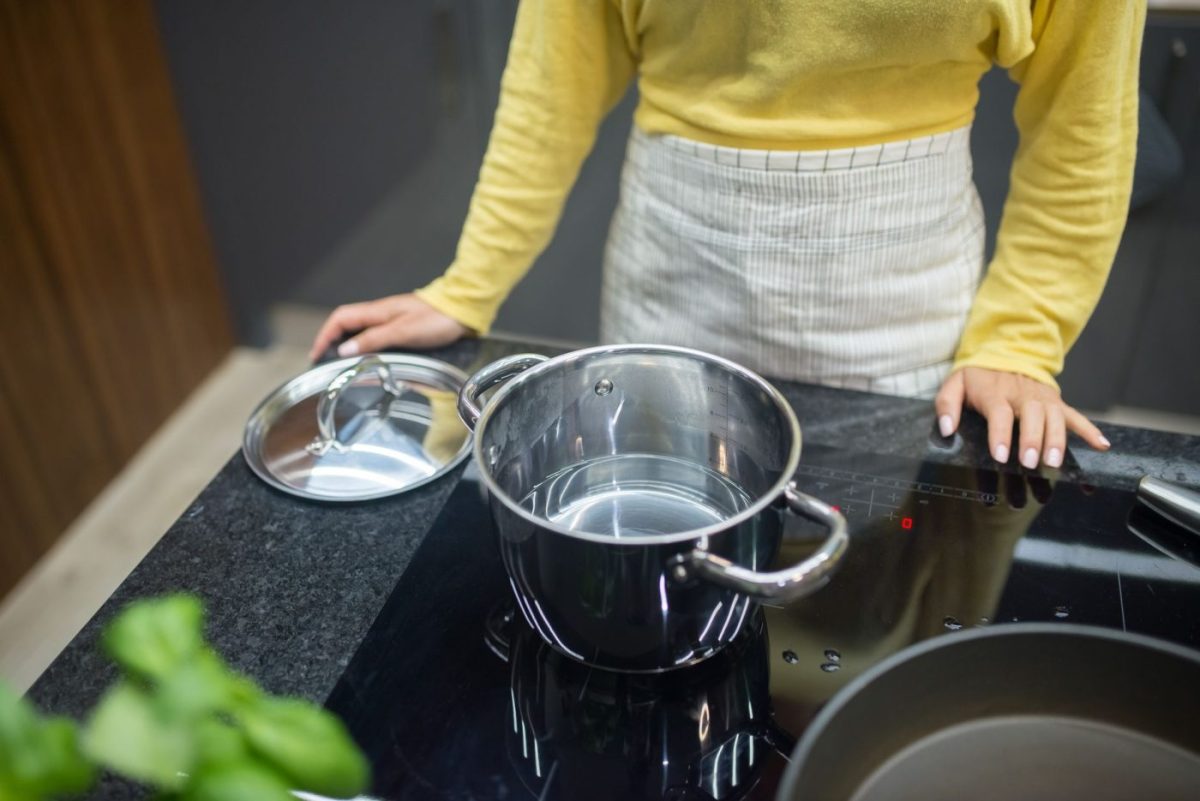 A person cooking on an induction cooktop in a modern residential kitchen, demonstrating everyday use.